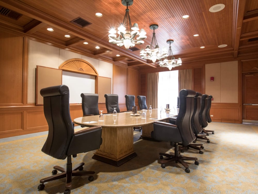 interior view of a boardroom with wooden wall panels and a table surrounded by executive offer chairs sits in the middle of the room