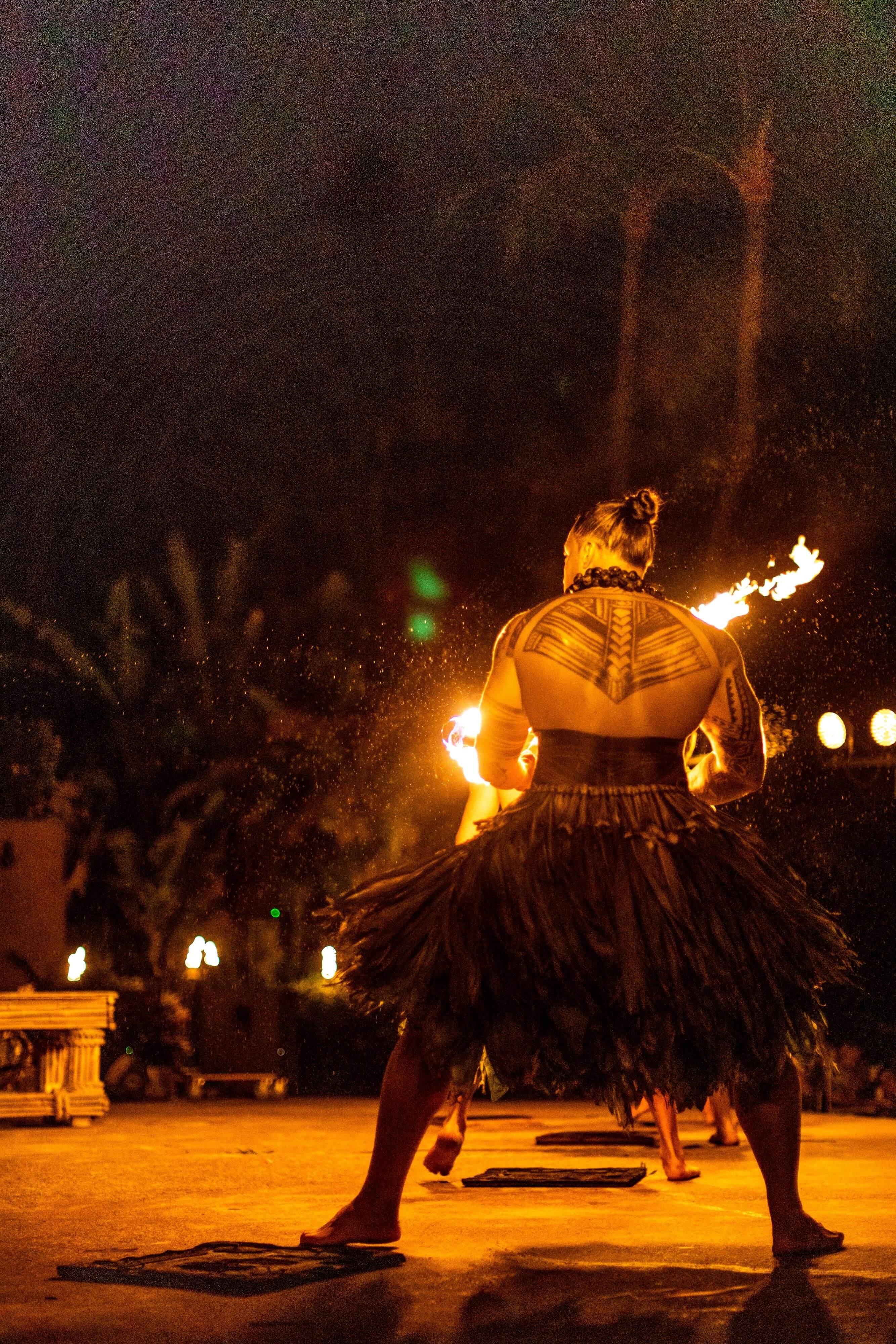 fire performer stands with his back to the camera with large tattoo on his upper back