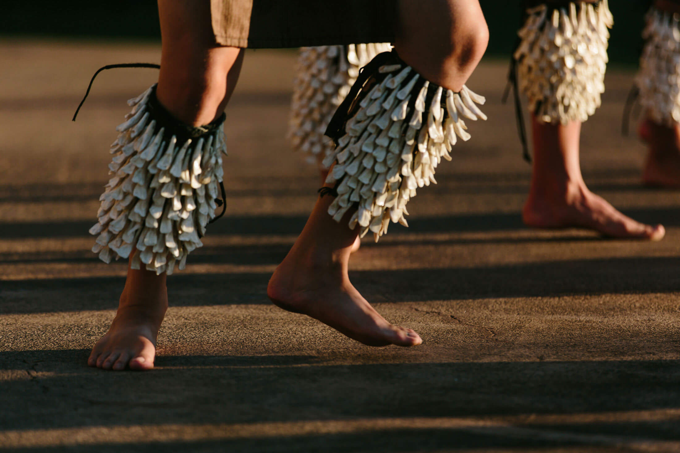 two sets of legs hop while wearing shells and dancing the luau