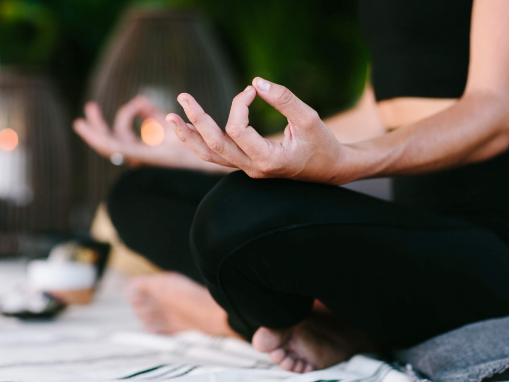 close up of woman's hands laying on her legs while in mediation 