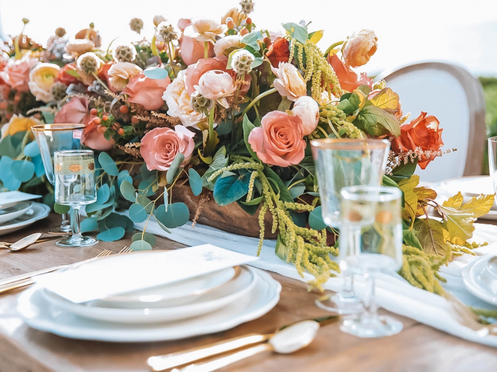 a table with pink and green floral centerpeice complete with table setting for event