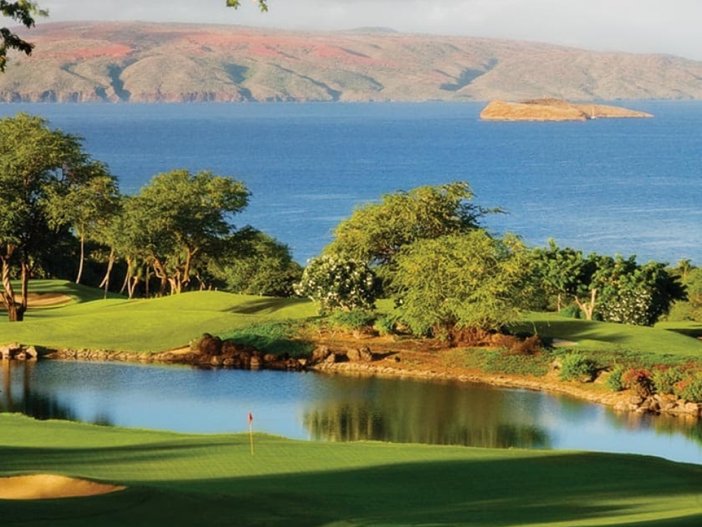 golf course sits on the edge of the ocean with the mountains in the background