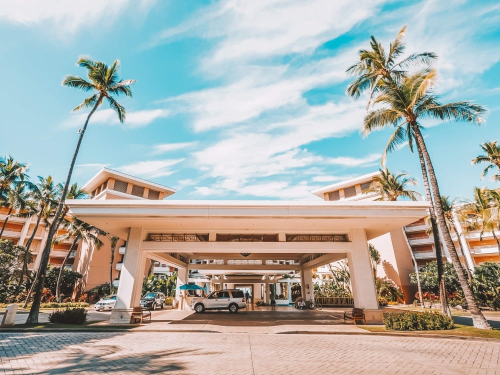 entrance of the Grand Wailea resort with cloudy blue sky and palm trees