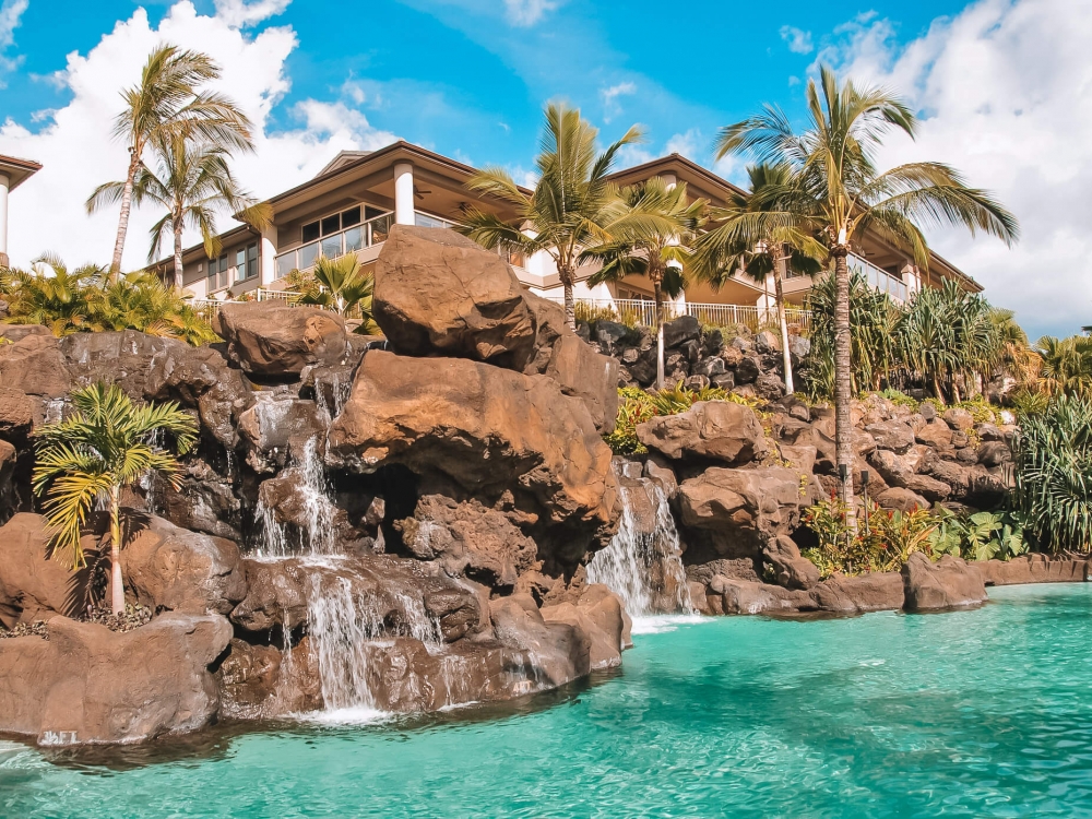 a rock wall with waterfalls drop into a pool in the foreground