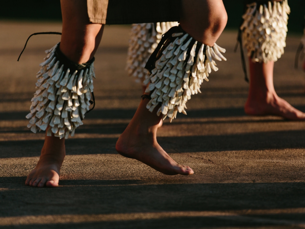 two sets of legs hop while wearing shells and dancing the luau