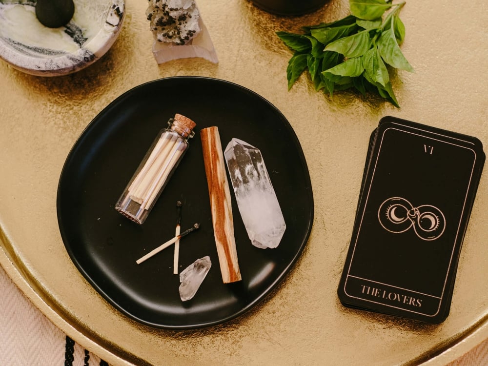 flatlay of candles, phone, and astrology reading on circular wooden table