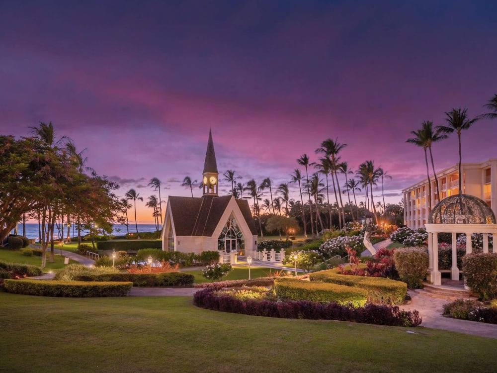 small white chapel sits on the well manicured grounds of Grand Wailea resort with a purple evening sky