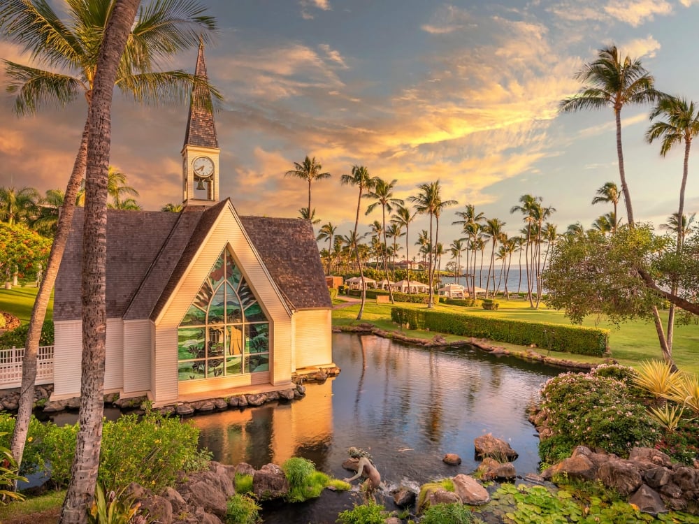 close up of a white chapel with stained glass window set beside a small pond on the well-manicured grounds of Grand Wailea resort 