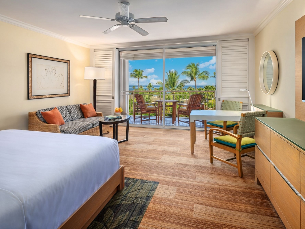 interior view of Ocean View King bed and seating area with patio door with an exterior view in the background