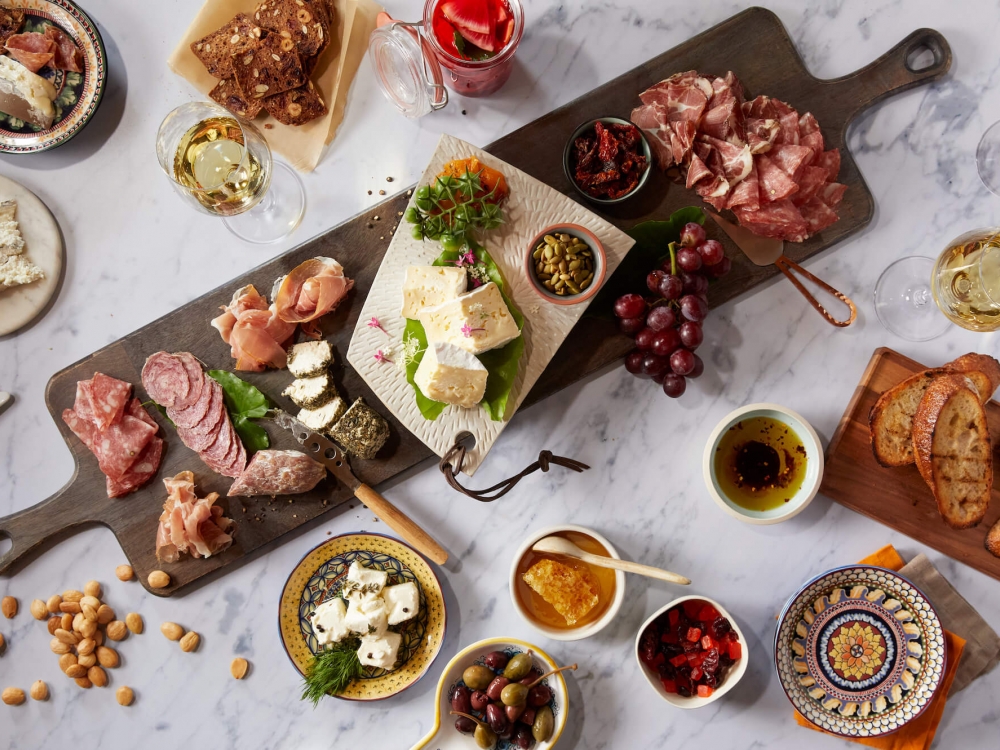 charcuterie board surrounded by assorted dishes