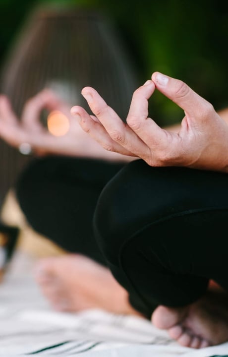 close up of woman's hands laying on her legs while in mediation 