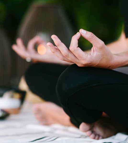 close up of woman's hands laying on her legs while in mediation 