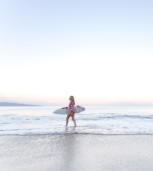 a person holding a surfboard walks along the ocean's edge