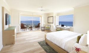 interior view of bed and seating area with patio door with an exterior view in the background