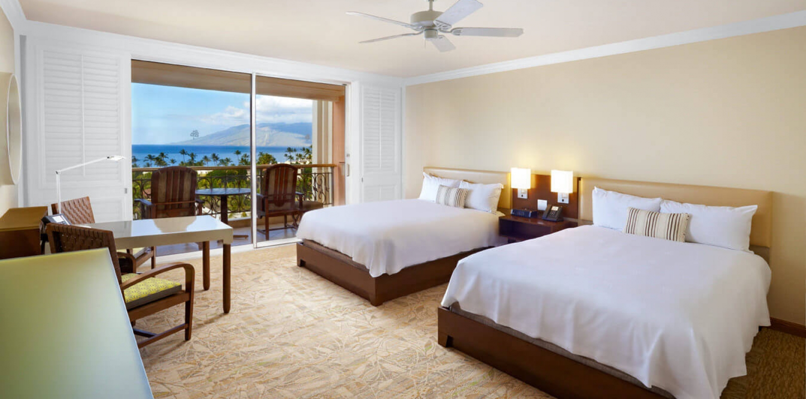 two Queen beds and seating area in Queen Oceanview room with patio doors give view of outside
