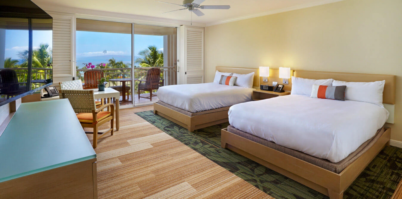 two beds and seating area in Signature room with patio doors give view of outside