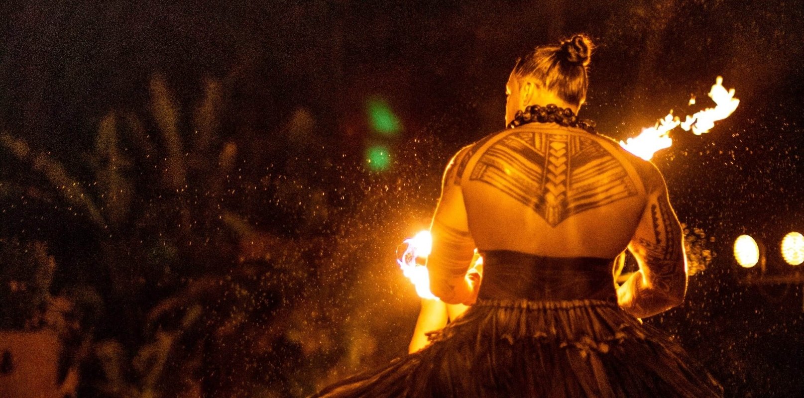 fire performer stands with his back to the camera with large tattoo on his upper back