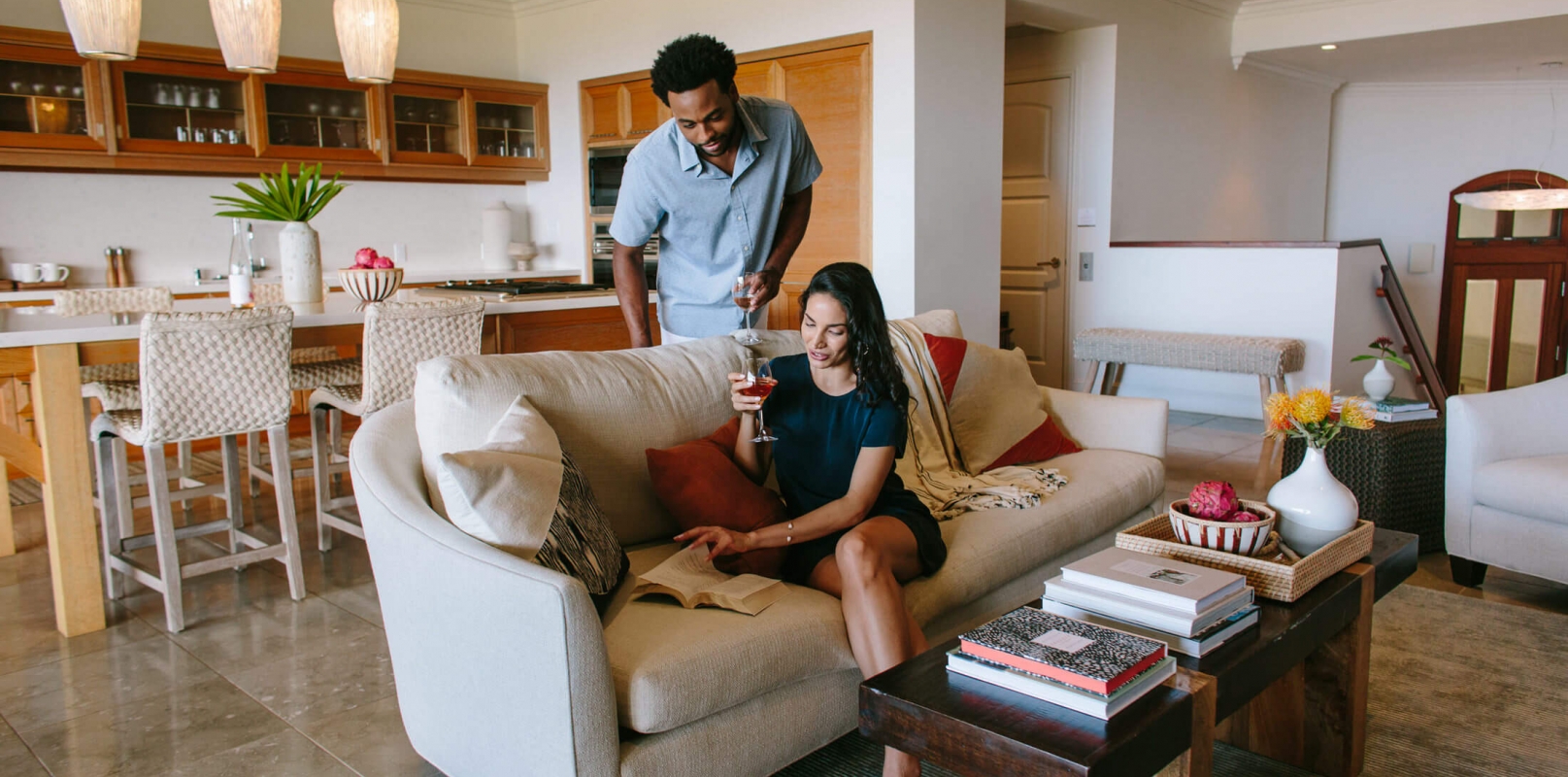 a couple look at a book while drinking wine in a comfy seating area