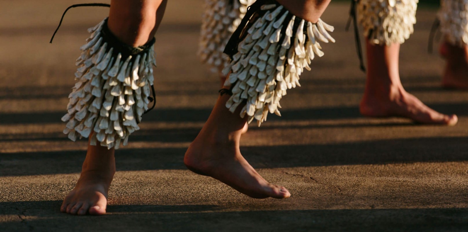 two sets of legs hop while wearing shells and dancing the luau