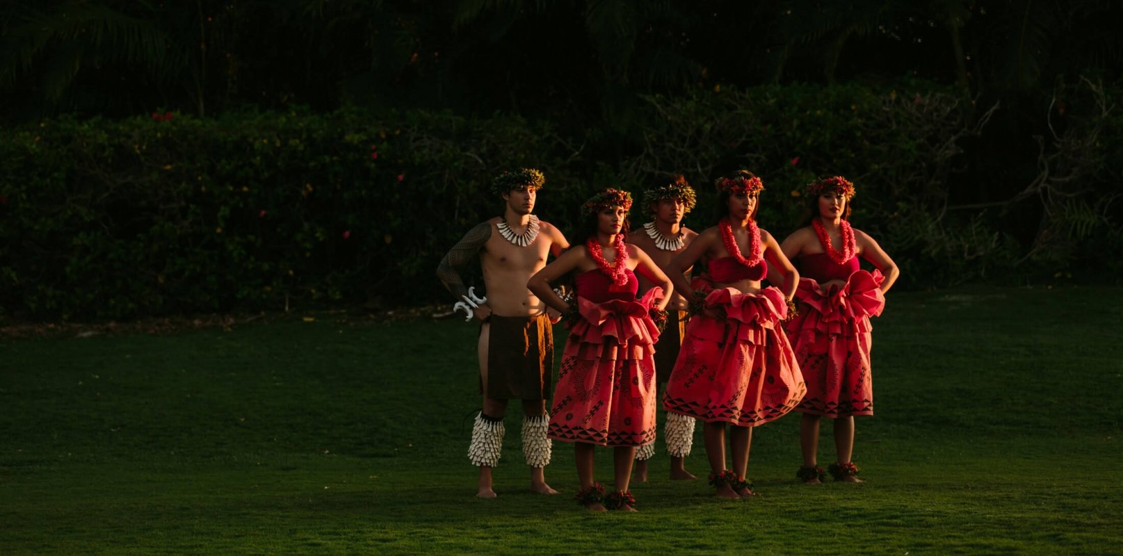 a group of women in red and men dance in a field