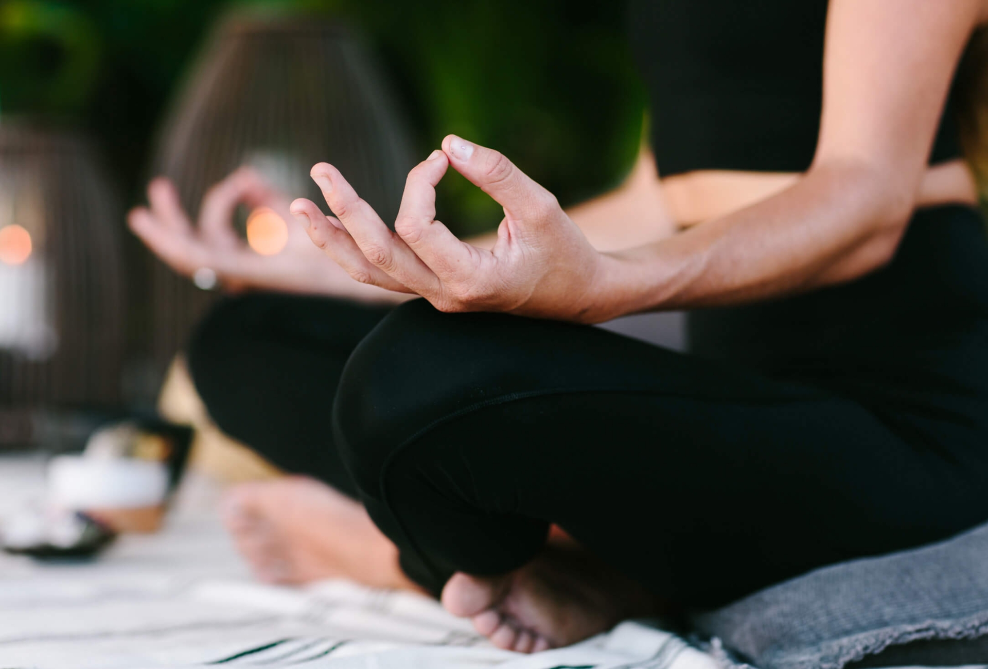 close up of woman's hands laying on her legs while in mediation 