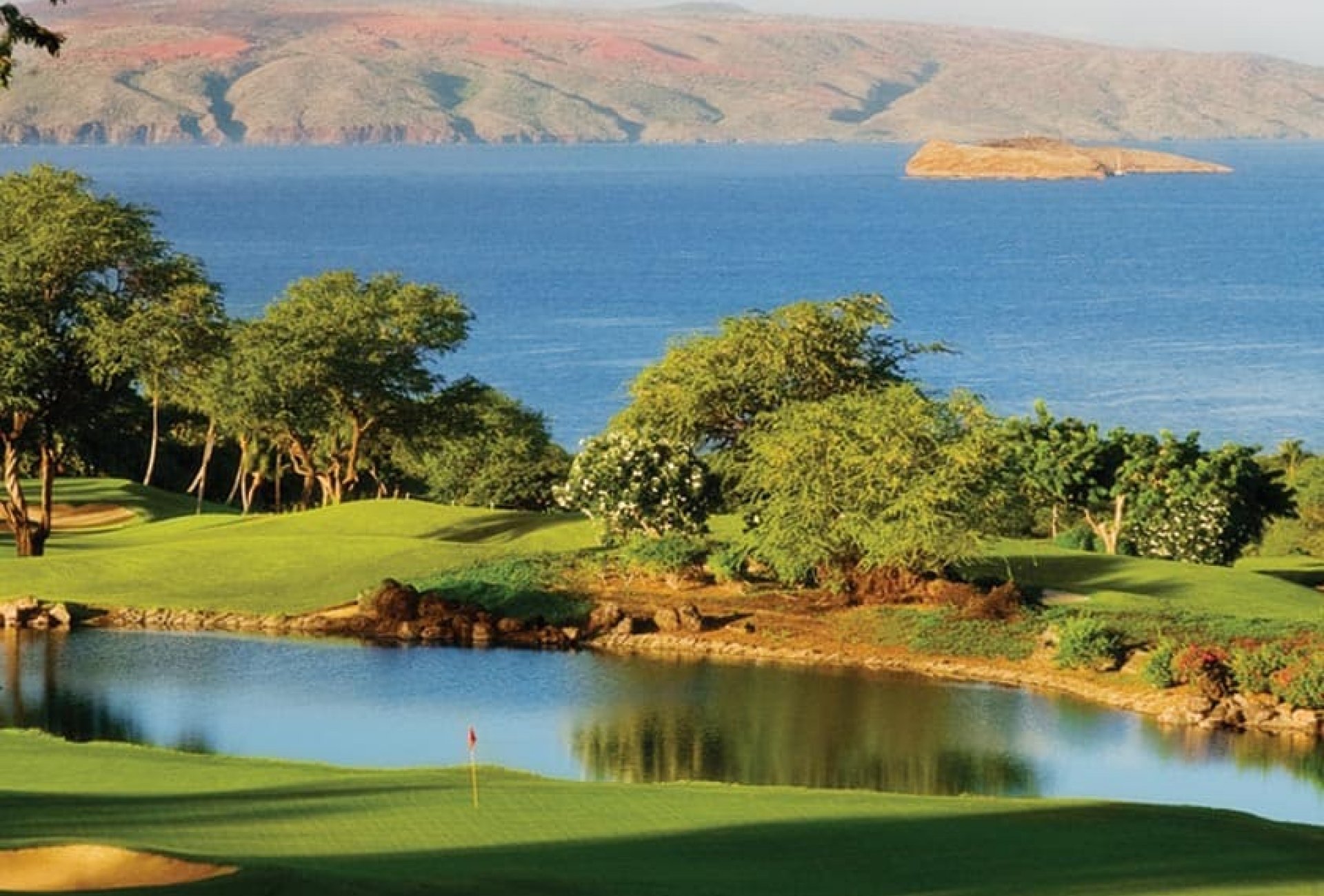 golf course sits on the edge of the ocean with the mountains in the background