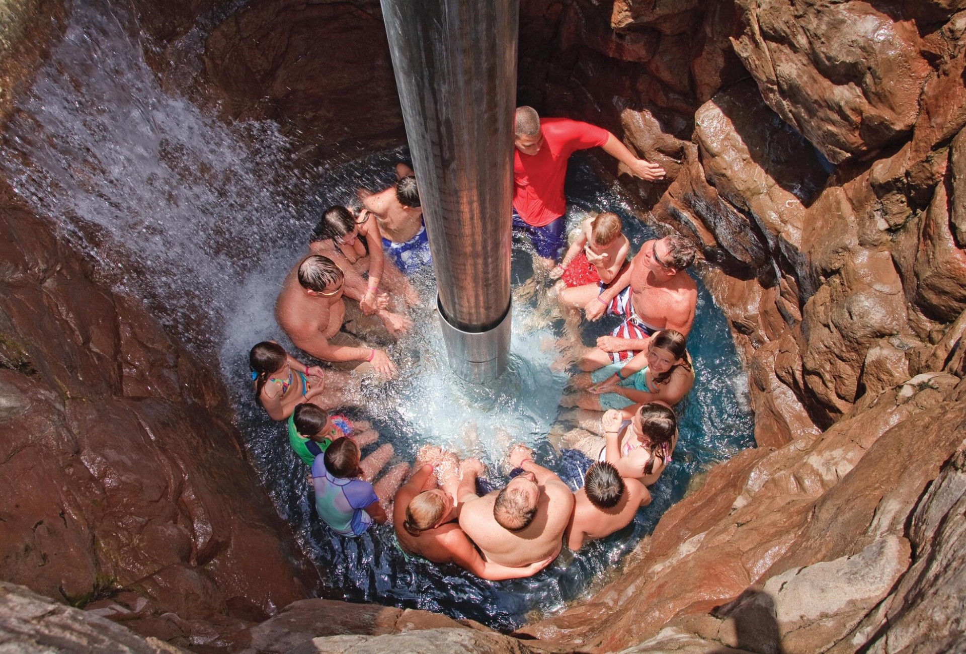 a group of people in a stone water elevator while water pours down onto them