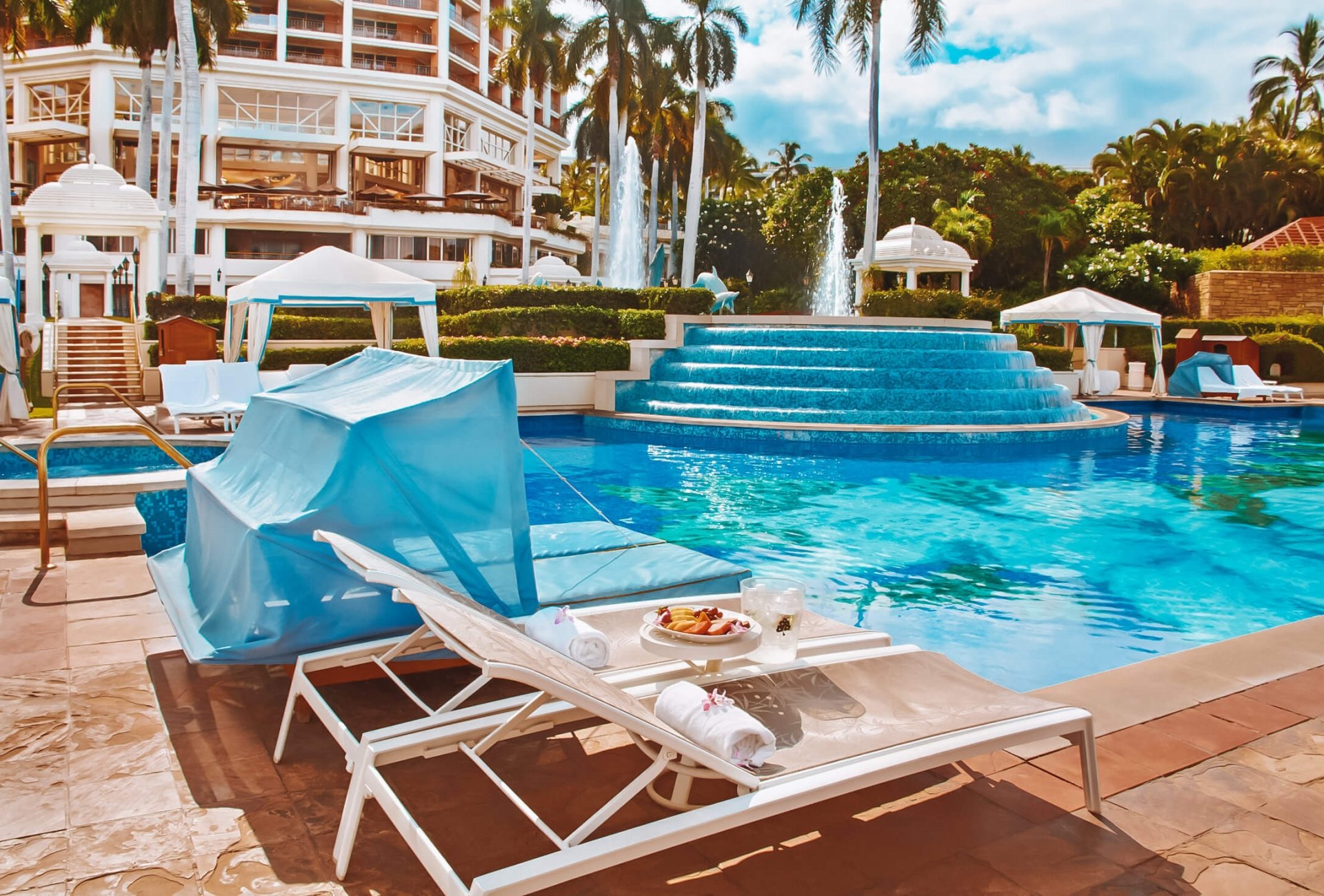 cabanas and lounge chairs are set up alongside a pristine blue pool