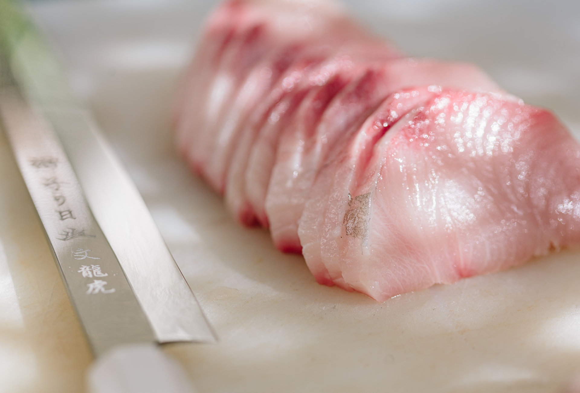 Hamachi on cutting board with sushi knife