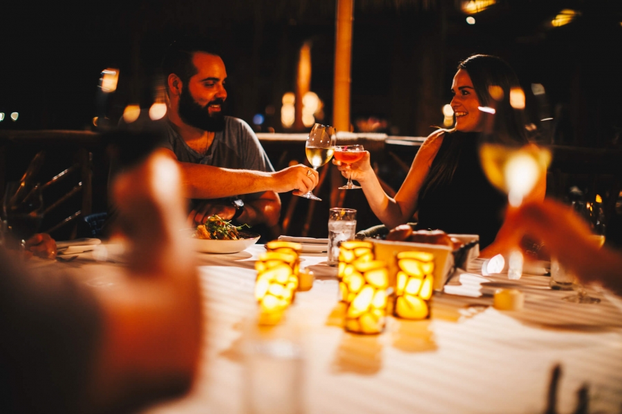 two people cheers their cocktails in the dimly lit humuhumunukunukuapua'a restaurant at dusk