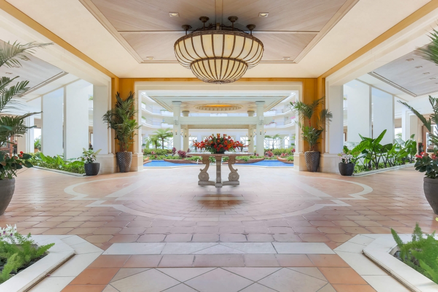 a floral arrangement sits under a chandelier in the middle of a stone lobby