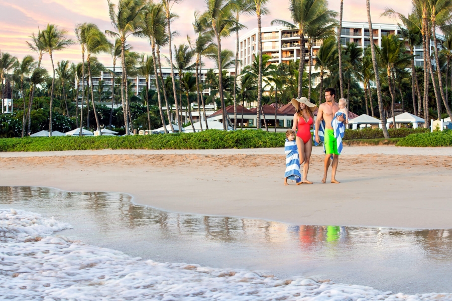 a family walk on the beach with palm trees in the background