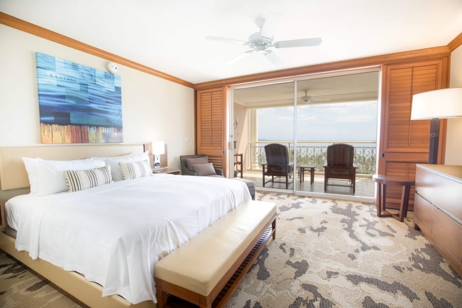 king bed and seating area in Napua Club Royal room with patio doors give view of outside