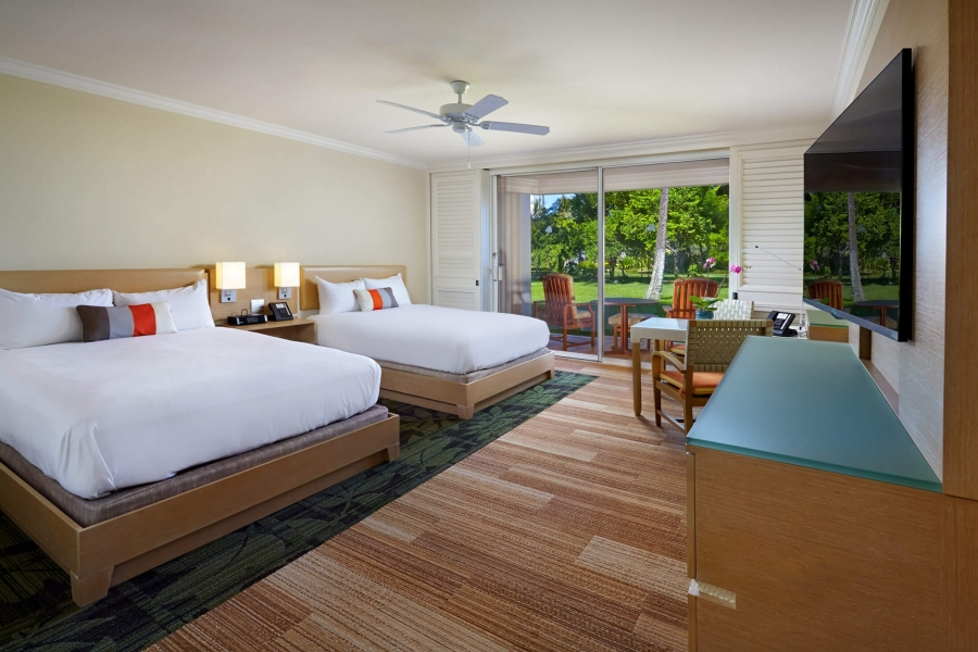 two beds and seating area in Signature room with patio doors give view of outside