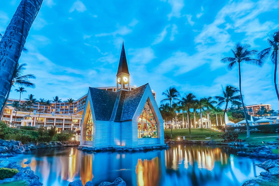 the Grand Wailea wedding chapel is lit up from the inside while the sun sets on the resort