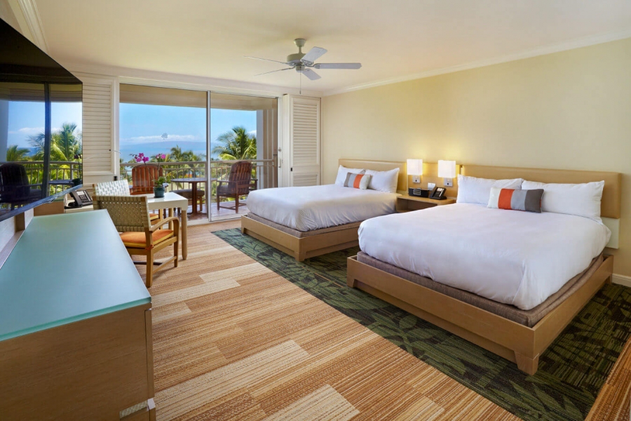 two beds and seating area in Signature room with patio doors give view of outside