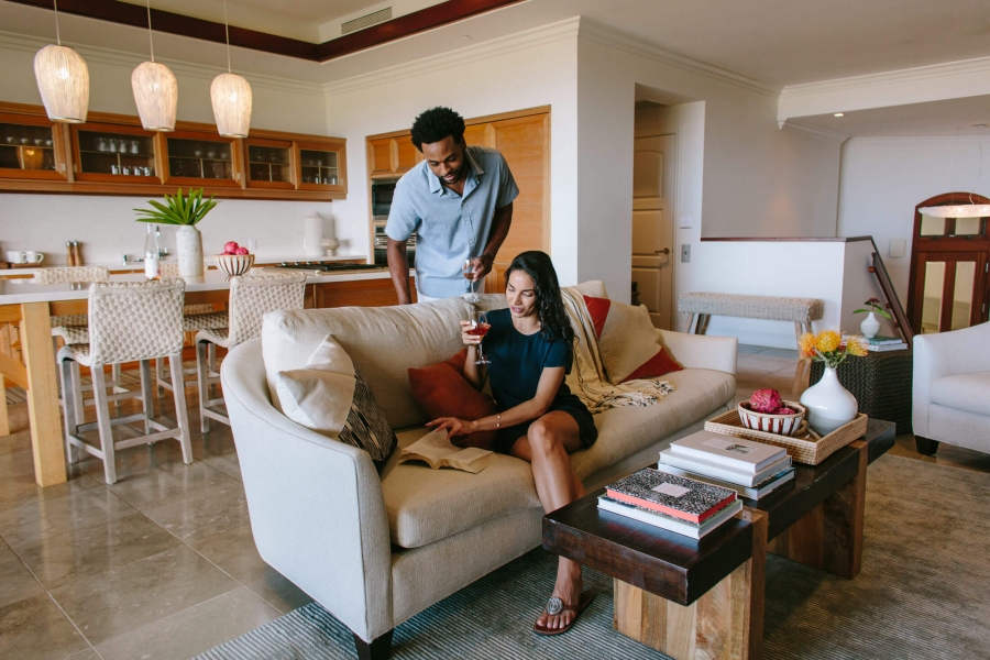 a couple look at a book while drinking wine in a comfy seating area