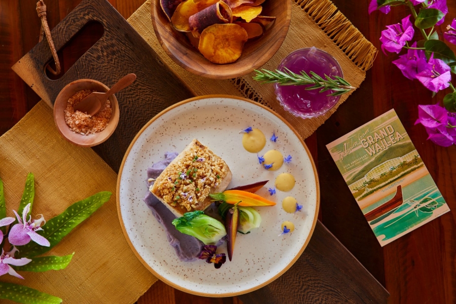 flatlay of a plate of fish beside a red cocktail on a wooden table