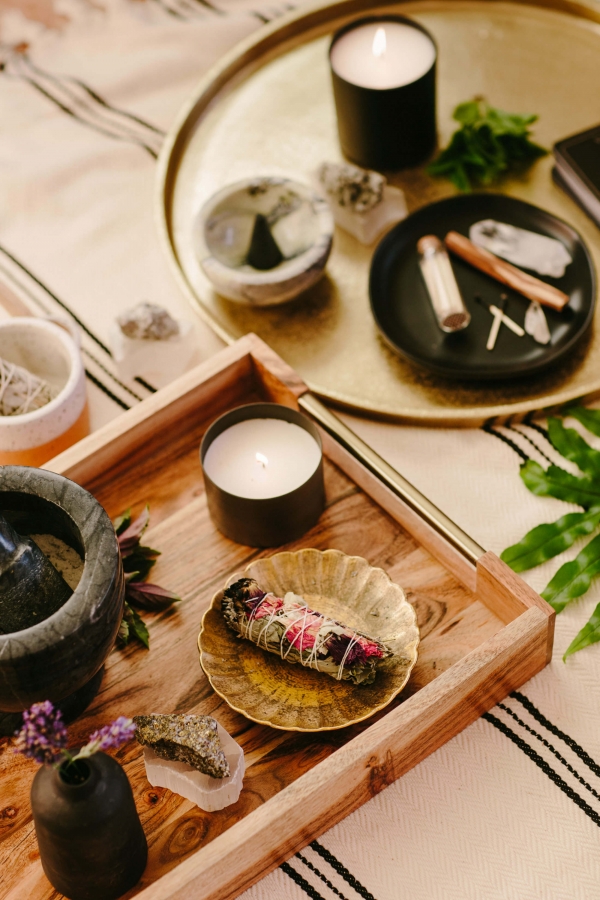 flatlay of candles, phone, and astrology reading on circular wooden table