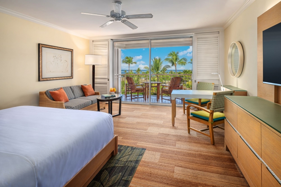 interior view of Ocean View King bed and seating area with patio door with an exterior view in the background